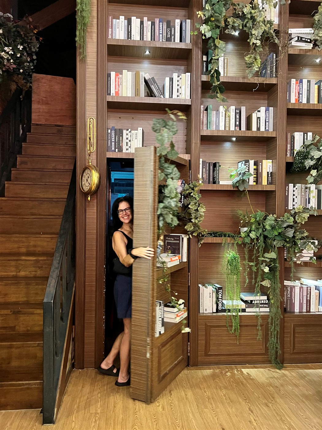 Laura Garcia stepping out of a hidden bookcase door